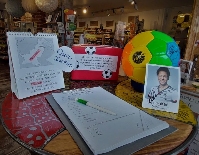 Fußballquiz, Quizinfos, eine Box für die Teilnahmezettel, Ball in Regenbogenfarben plus Autogrammkarte von der ehemaligen Fußball-Nationalspielerin Célia Šašić