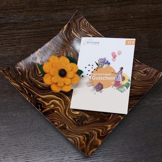 Braune Holzschale, darauf ein Gutschein und eine orangene Filzblume